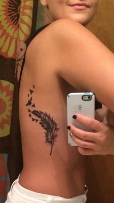 Tatouage plume sur les côtes avec des petits oiseaux noirs